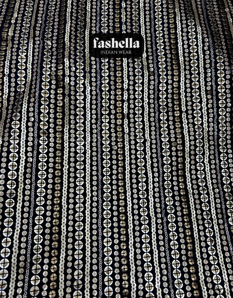May include: Black fabric with a repeating pattern of white and gold sequins. The fabric has a label that reads "fashella INDIAN WEAR".
