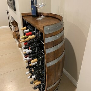 May include: A wooden wine rack made from a barrel with a metal top and metal bands. The rack holds multiple bottles of wine and is a great way to store and display your wine collection.