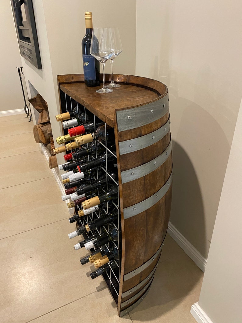 May include: A wooden wine rack made from a barrel with a metal top and metal bands. The rack holds multiple bottles of wine and is a great way to store and display your wine collection.