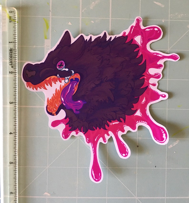 May include: A sticker of a black wolf with a purple tongue sticking out, dripping with pink paint. The wolf has a purple eye and a white tooth.