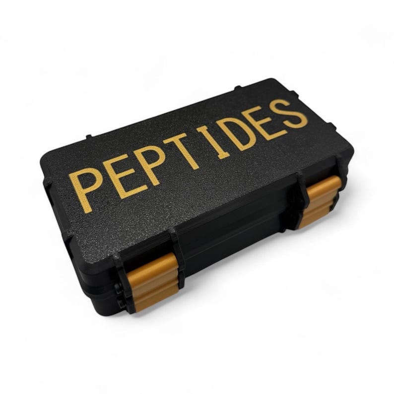May include: A black rectangular case with the word "PEPTIDES" in gold lettering. The case has gold-colored clasps and hinges. The case is likely used for storage or transport of small items.
