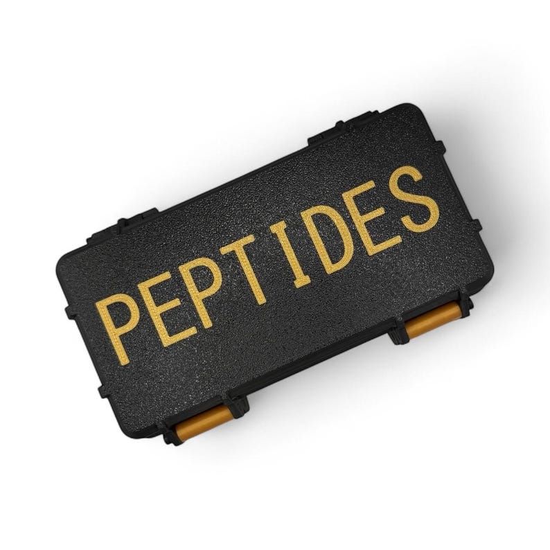 May include: A black rectangular case with the word "PEPTIDES" in gold lettering. The case has a textured surface and gold-colored handles. The case is closed and appears to be made of a durable material.