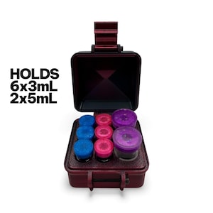 May include: A burgundy case with an open lid, holding eight small jars in blue, pink, and purple. The case has a handle and a latch. Text on the left says "HOLDS 6x3mL 2x5mL".