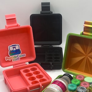 May include: Several small, colorful cases with hinged lids. One is open, revealing a tray with circular compartments. Another case contains small glass vials and a bottle labeled "Bacteriostatic Water". The cases are in shades of pink, black, and green.