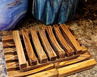 May include: A wooden soap dish with a slatted design. The dish is made of natural wood and has a rustic look.