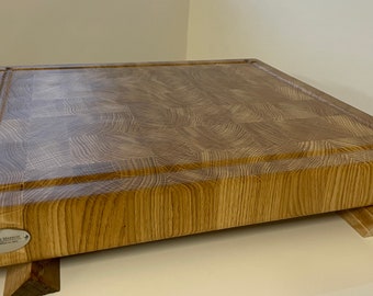 May include: A large, rectangular wooden cutting board with a checkered pattern on the surface. The board has a thick, rounded edge and a small metal tag with the text "Jamie Martin" on the bottom left corner.