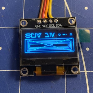Könnte beinhalten: Ein kleiner blauer LCD-Bildschirm mit schwarzem Text, der "3.1V" und "--.--" auf einer schwarzen Platine mit goldenen Steckverbindern anzeigt. Die Platine ist mit "GND", "VCC", "SCL" und "SDA" beschriftet.
