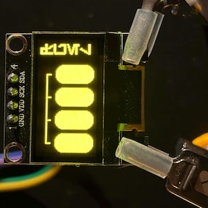 May include: A small black circuit board with a yellow LED display that reads "2.1V~" and has the labels "GND", "VDD", "SCK", and "SDA".