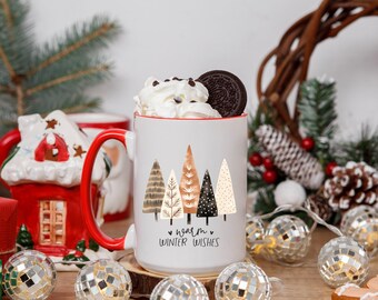 May include: A white ceramic mug with a red handle and rim, filled with whipped cream and a cookie. The mug features a design of stylized trees and the text "warm winter wishes". The mug is surrounded by holiday decorations.