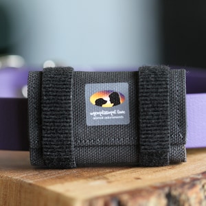 May include: A black velcro dog collar attachment with a grey patch that says "unconditional love animal adornments".