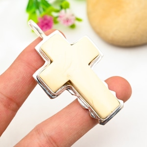 Peut inclure: Un pendentif en forme de croix blanche avec un cadre argent&eacute;. La croix est faite d'un mat&eacute;riau blanc lisse et a une surface l&eacute;g&egrave;rement textur&eacute;e. Le cadre argent&eacute; est orn&eacute; et pr&eacute;sente un design d&eacute;taill&eacute;.