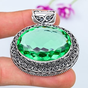 May include: A silver pendant featuring an oval green gemstone set within a filigree design.
