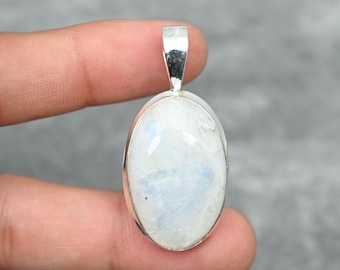 May include: A silver pendant with a white oval moonstone. The pendant is set in a silver bezel and has a silver bail.