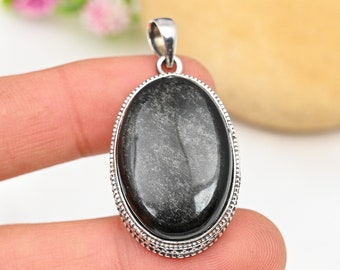 May include: A silver pendant with a black oval gemstone set in a silver bezel. The pendant has a detailed silver border.