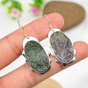 Peut inclure: Une paire de boucles d'oreilles en argent avec des pierres ovales vertes et violettes serties dans un cadre argenté festonné.