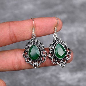 Puede incluir: Un par de pendientes de plata con gotas de piedras preciosas verdes. Los pendientes tienen un delicado diseño de filigrana.