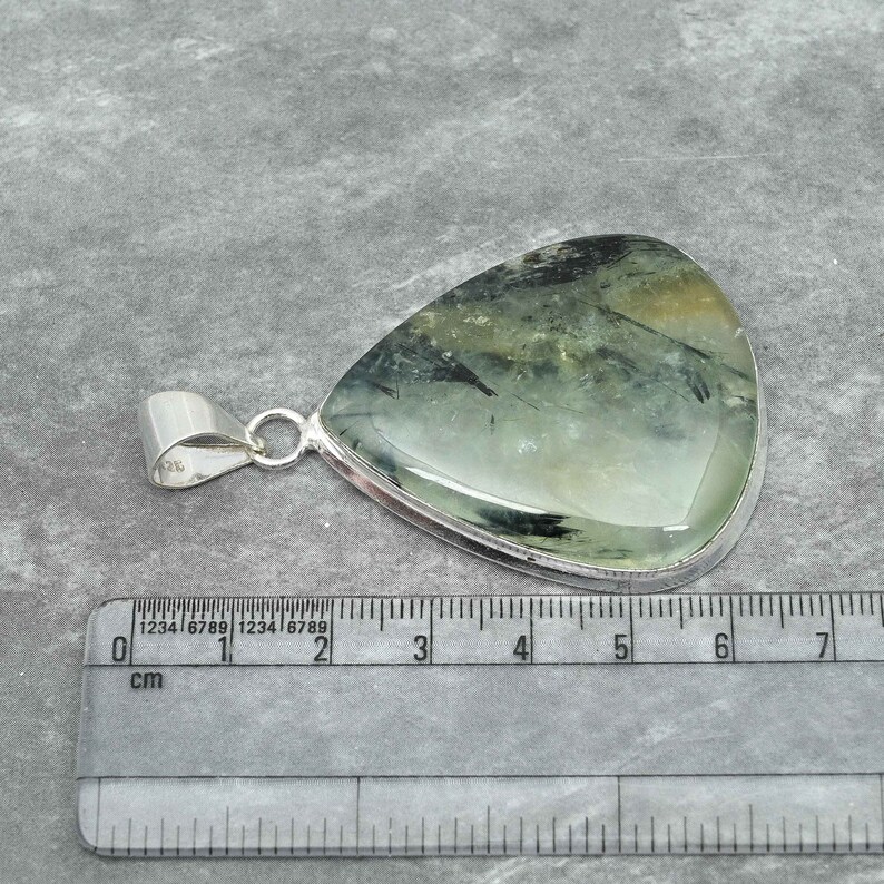 Peut inclure: Un pendentif en argent avec une pierre pr&eacute;cieuse verte et noire. Le pendentif mesure environ 5 cm de long.