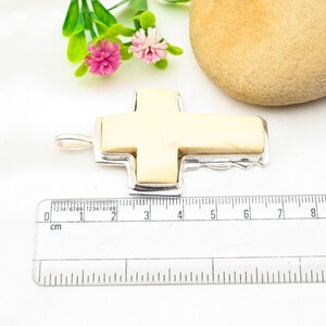 Peut inclure: Un pendentif en forme de croix en argent avec une incrustation en os blanc. Le pendentif mesure environ 4 cm de long.
