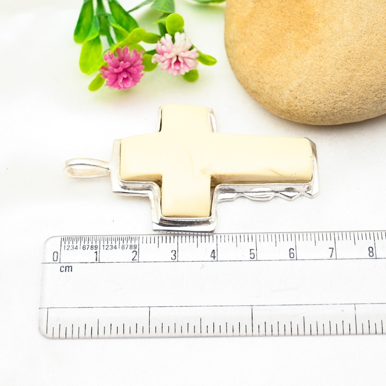 Peut inclure: Un pendentif en forme de croix en argent avec une incrustation en os blanc. Le pendentif mesure environ 4 cm de long.