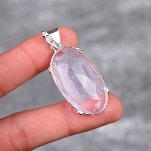 May include: A silver pendant featuring a large, oval-shaped, faceted, light pink rose quartz gemstone.