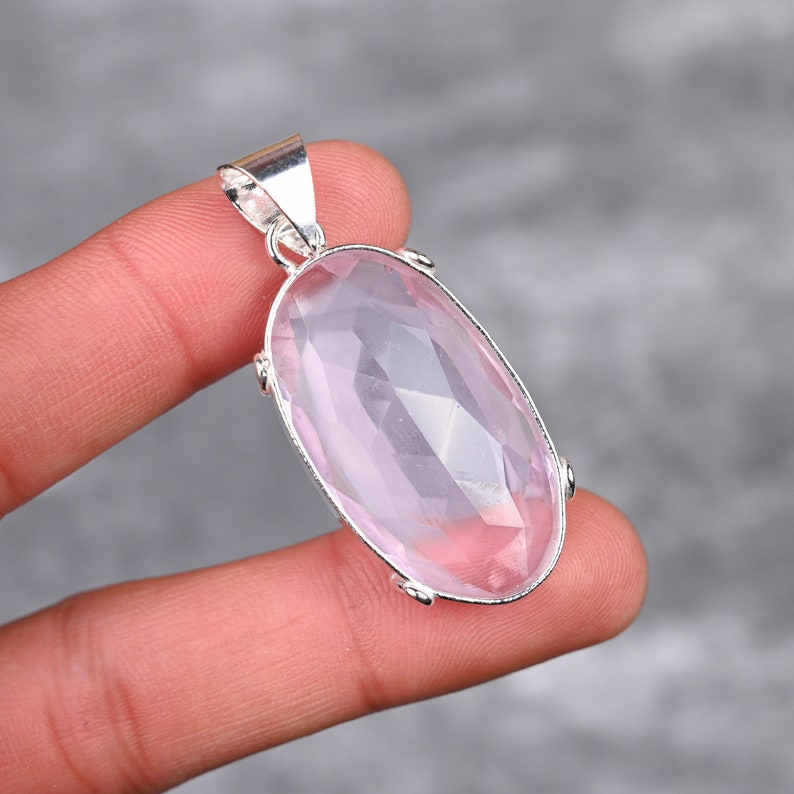 May include: A silver pendant featuring a large, oval-shaped, faceted, light pink rose quartz gemstone.