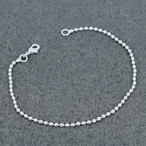 Peut inclure: Un bracelet à chaîne à billes de couleur argentée composé d'une série de petites perles sphériques uniformes reliées entre elles. Le bracelet comprend un fermoir mousqueton à une extrémité et un anneau circulaire à l'autre.