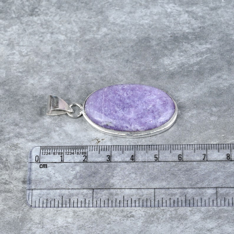 May include: A silver pendant featuring a light purple oval-shaped gemstone. The pendant measures approximately 3 cm in length.