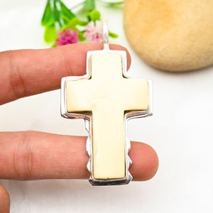 Peut inclure: Un pendentif en forme de croix en os blanc avec un cadre argent&eacute;. La croix est sertie dans un cadre argent&eacute; avec un bord festonn&eacute;.