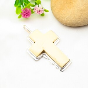 Peut inclure: Un pendentif en forme de croix blanche avec une bordure argent&eacute;e. La croix est faite d'un mat&eacute;riau blanc lisse et a une forme l&eacute;g&egrave;rement arrondie.