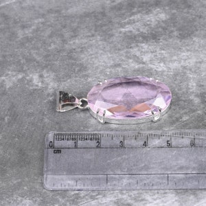 May include: A pale pink oval-shaped gemstone pendant with a silver setting. The pendant is approximately 2 cm in length.