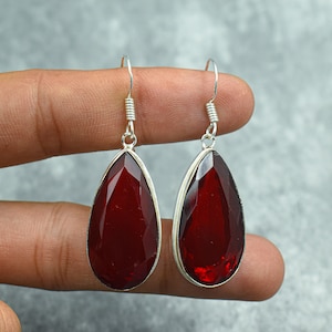 Può includere: Un paio di orecchini pendenti in argento con gocce di pietre preziose rosse a forma di lacrima.