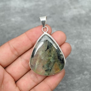 Peut inclure: Un pendentif en argent avec une pierre pr&eacute;cieuse verte et noire en forme de larme et une b&eacute;li&egrave;re en argent.