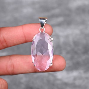 May include: A silver pendant featuring a large, faceted, oval-shaped, light pink rose quartz gemstone.