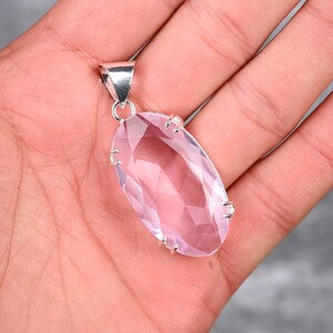 May include: A silver pendant featuring a large, faceted, oval-shaped, light pink amethyst gemstone.