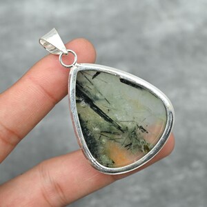 Peut inclure: Un pendentif en argent avec une pierre pr&eacute;cieuse verte et noire en forme de larme. La pierre pr&eacute;cieuse est sertie dans une b&eacute;li&egrave;re en argent.
