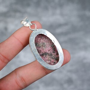 May include: A silver pendant with a pink and black rhodochrosite stone set in an oval bezel.