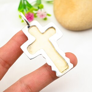 Peut inclure: Pendentif en forme de croix en argent avec une incrustation de pierre blanche. La croix a un bord festonn&eacute; d&eacute;taill&eacute;.