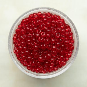 Puede incluir: Un recipiente de plástico transparente lleno de cuentas de vidrio rojas.