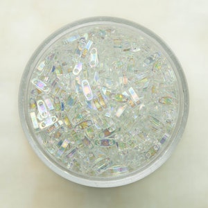 May include: A clear glass bowl filled with iridescent glass beads. The beads are small and have a rectangular shape.