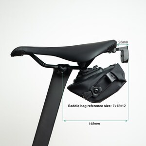 May include: A black bicycle saddle with a black saddle bag attached underneath. The image includes technical annotations with measurements of 25mm, 145mm, and a saddle bag reference size of 7x12x12. The seat post is black and vertical.
