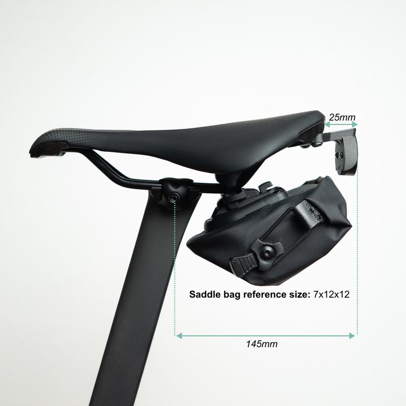 May include: A black bicycle saddle with a black saddle bag attached underneath. The image includes technical annotations with measurements of 25mm, 145mm, and a saddle bag reference size of 7x12x12. The seat post is black and vertical.