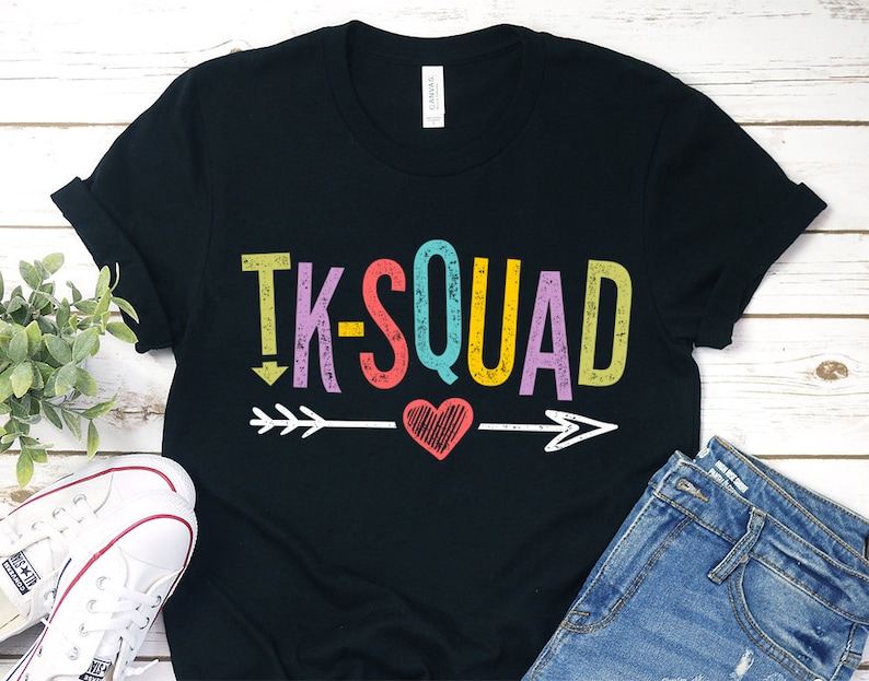 May include: Black t-shirt with the text "TK-SQUAD" in rainbow colours with an arrow and heart graphic.