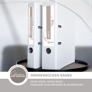 Puede incluir: Dos archivadores blancos con etiquetas que dicen "ABRECHNUNGEN" y "MIETE". Las etiquetas tienen una franja marrón y un diseño floral. Los archivadores están sobre una bandeja negra. El texto en la parte inferior dice "ORDNERRÜCKEN RANKE" y "DEINE IDEEN, MEINE BASIS - VORLAGEN ZUM ANPASSEN & AUSDRUCKEN."