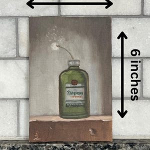 May include: Oil painting of a green gin bottle with a white label and a single white flower. The artwork is 4 inches wide and 6 inches tall. The bottle is labeled "Tanqueray" and is set against a neutral background.
