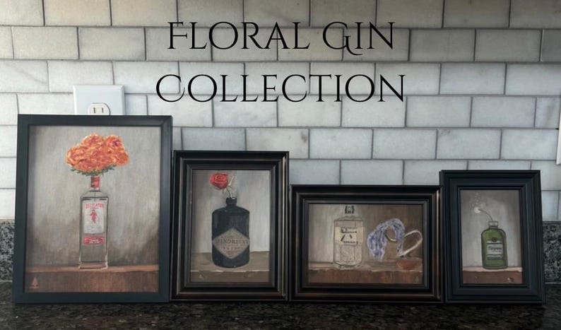 May include: A collection of four framed paintings featuring floral arrangements in gin bottles. The paintings are in black frames and are displayed against a white tile background. The text "FLORAL GIN COLLECTION" is at the top.