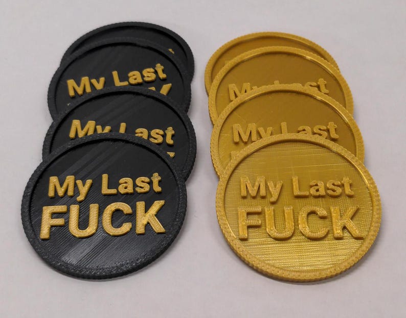 May include: A collection of black and gold round tokens. Each token has the phrase "My Last FUCK" in gold lettering. The tokens are arranged in two groups, one black and one gold.