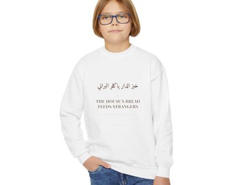 Sudadera de cuello redondo con la frase "El pan de la casa alimenta a extraños" / Cita en escritura árabe