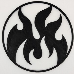 Può includere: Un disegno di fiamme nere all'interno di una cornice circolare. Le fiamme sono stilizzate e riempiono il cerchio, creando una grafica audace su sfondo bianco. Il design è semplice e moderno.