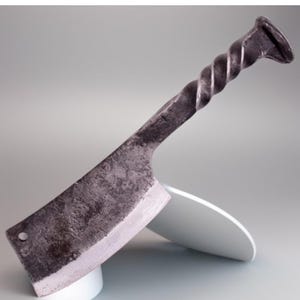 May include: A hand-forged cleaver with a twisted metal handle. The blade is made of steel and has a rustic finish. The handle is made of metal and has a twisted design.