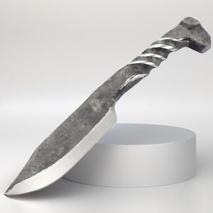 May include: A hand-forged knife with a twisted metal handle and a sharp blade. The knife is resting on a white surface.